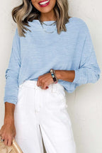 Woman wearing a casual Beau Blue solid color batwing long sleeve top with loose fit and high elasticity paired with white pants