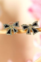Black rhinestone bow knot stud earrings with gold accents on a soft pink background