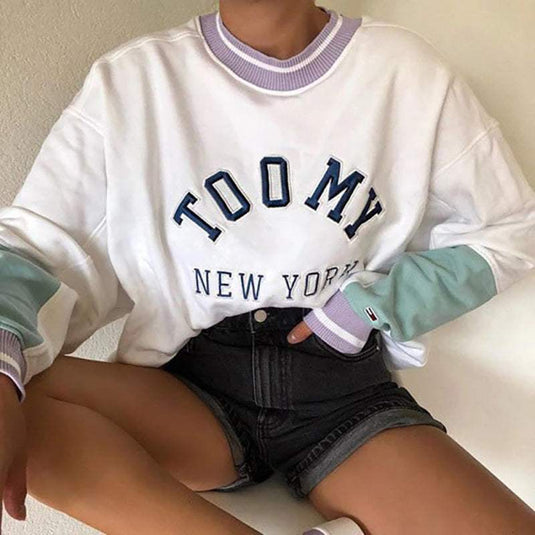 Soft long-sleeve knit top in white with multicolor details and printed "TOOMY NEW YORK" text