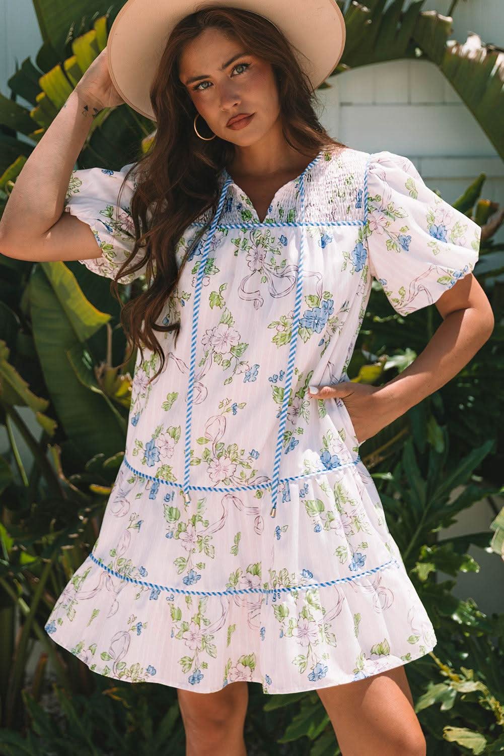 Woman wearing pink floral striped print mini dress with puff sleeves and tie split neck outdoors