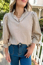 Woman wearing a straw yellow striped print seersucker blouse with tied cuffs and split neck