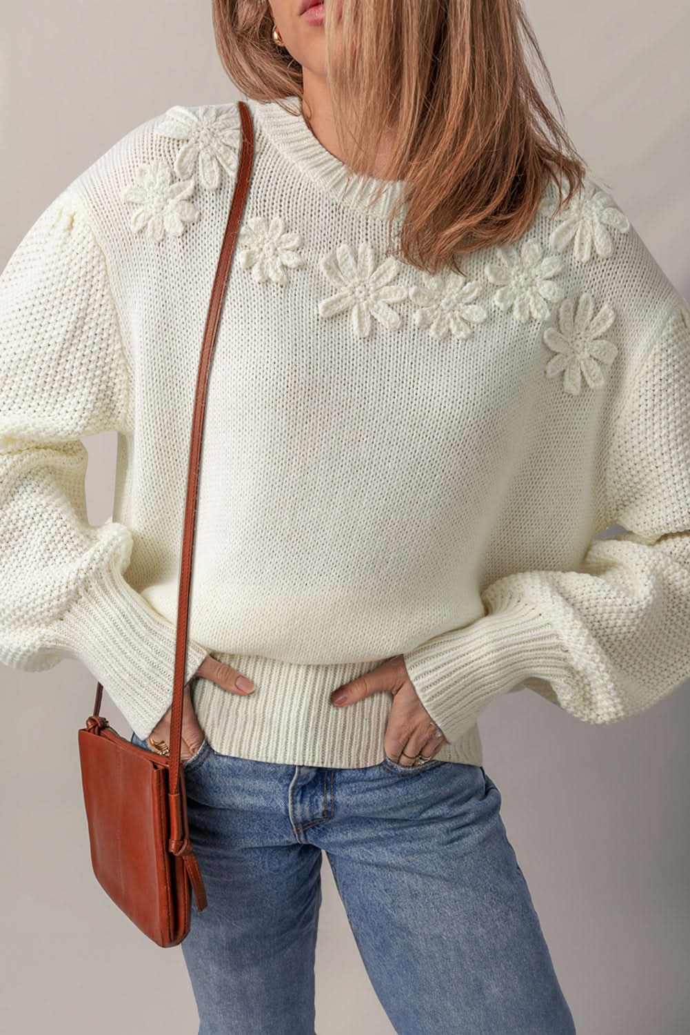 White sweater with flower applique detail and puff sleeves on woman wearing jeans and brown crossbody bag