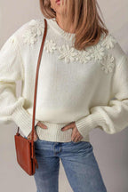White sweater with flower applique detail and puff sleeves on woman wearing jeans and brown crossbody bag