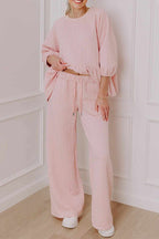 Woman wearing pink braided texture pants set with ruffle hem, drawstring waist, and wide-leg pants.
