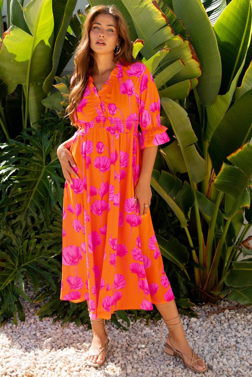 Woman wearing orange floral print frilly smocked V neck 3/4 sleeve long dress outdoors