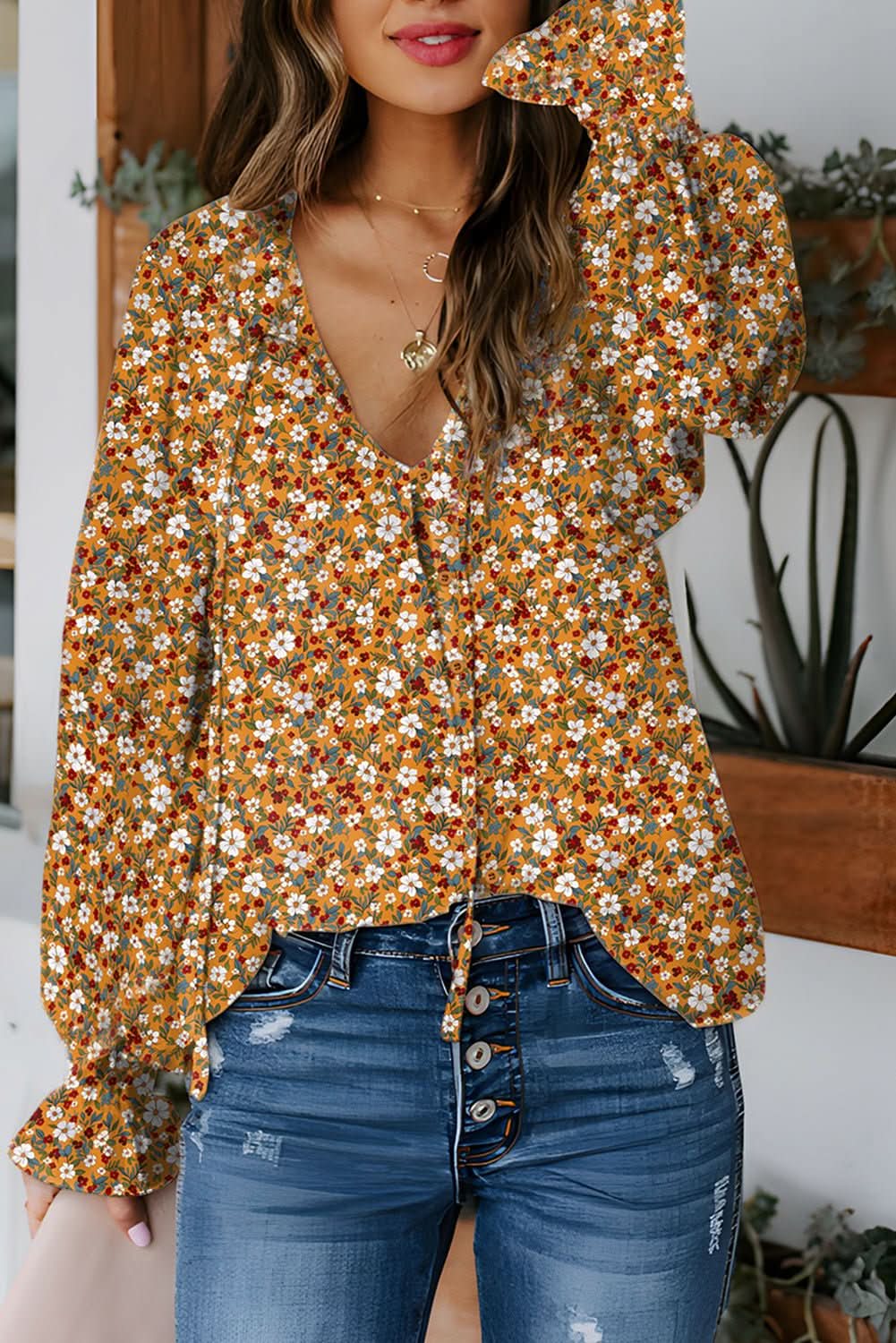 Orange boho floral ruffled bubble sleeve V-neck blouse on woman with denim jeans