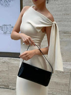 Woman wearing asymmetrical tied sleeveless maxi dress holding black handbag