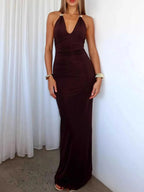 Woman wearing a black slit back halter neck maxi dress with ruched and tied details