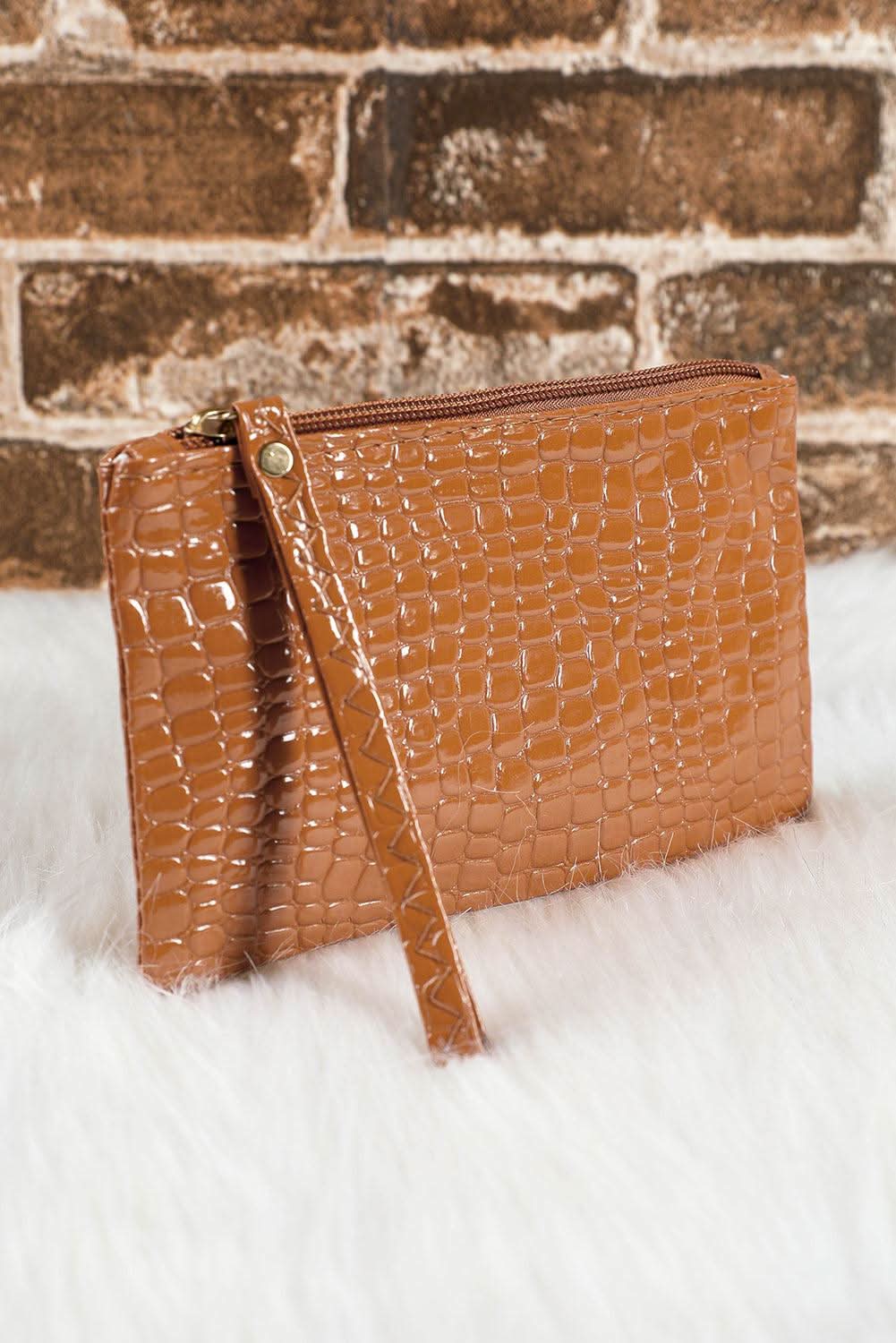 Brown crocodile pattern zipper wristlet wallet on white fur background