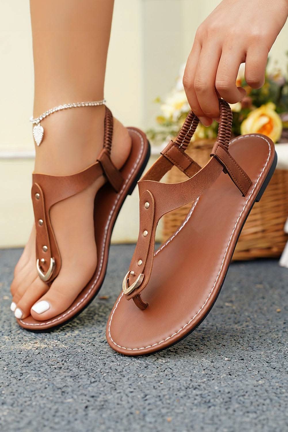Chestnut faux leather hollow out clip toe flat sandals on feet with ankle bracelet