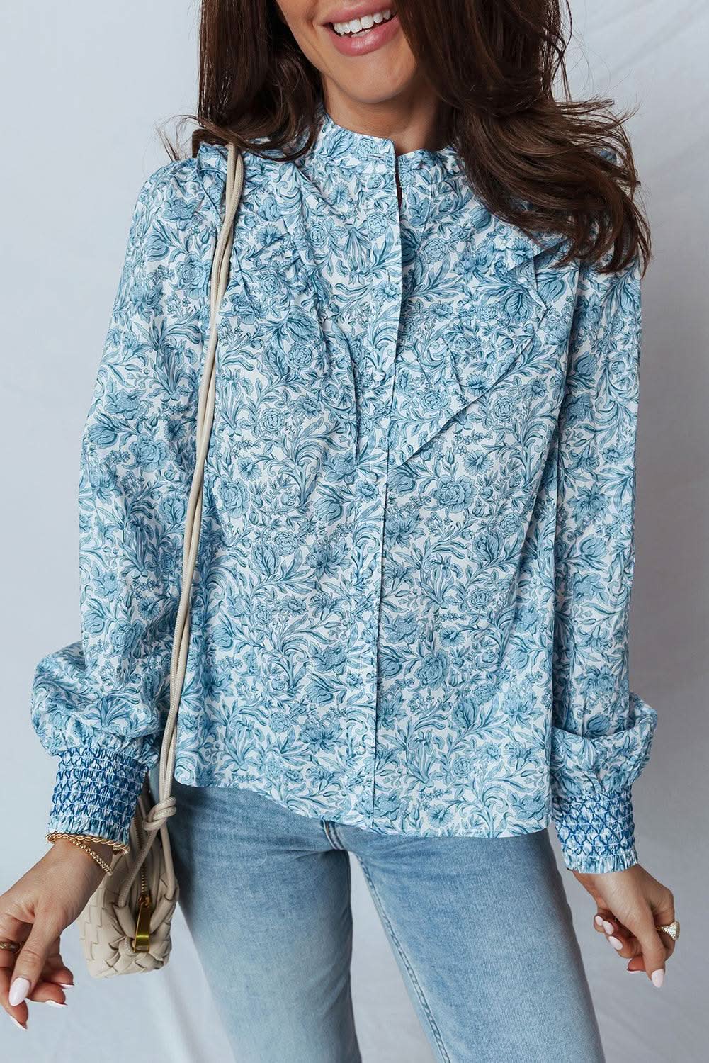 Woman wearing sky blue all over floral puff sleeve shirt with jeans and a white handbag