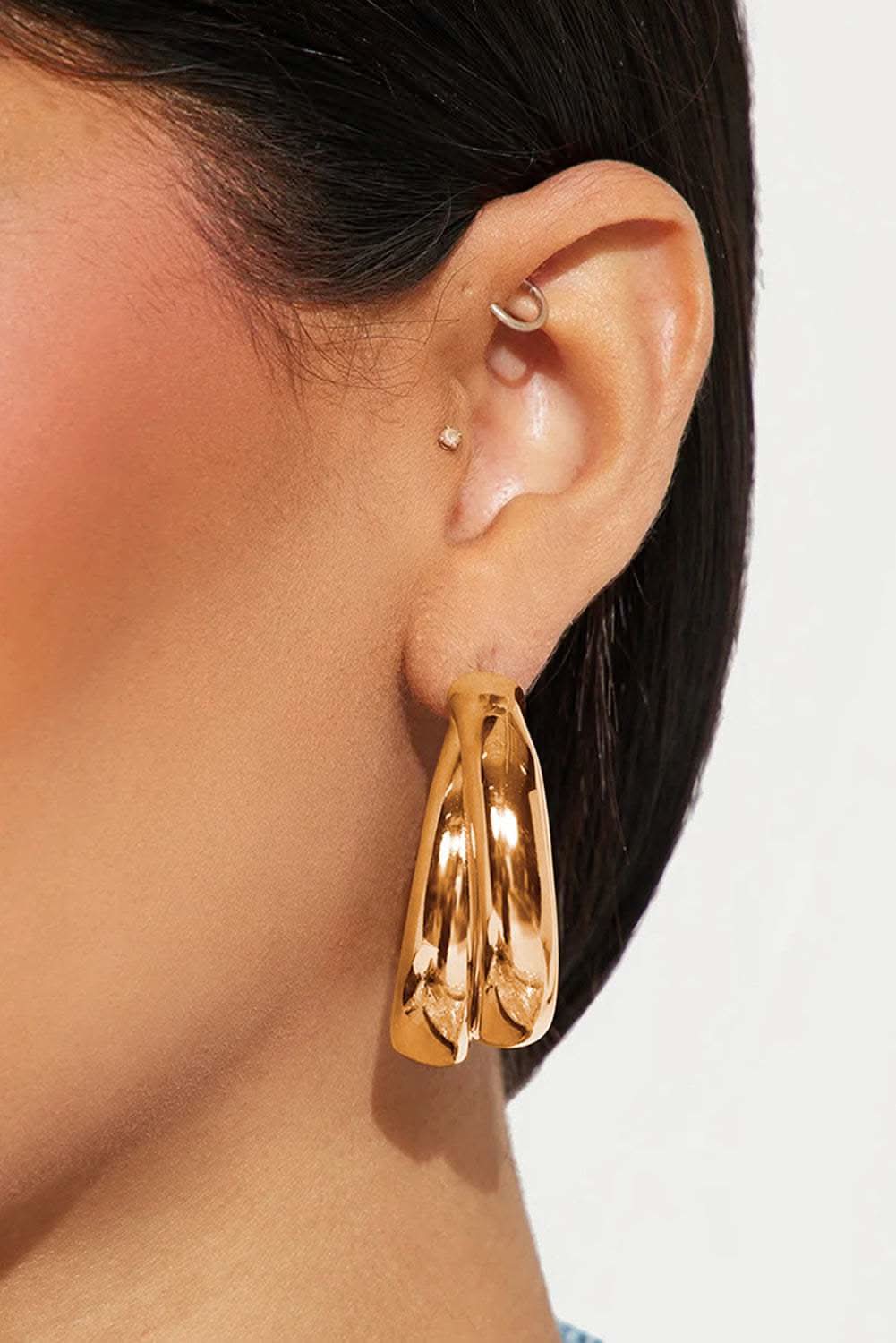 Close-up of gold layered hoop earrings with studded detailing on ear