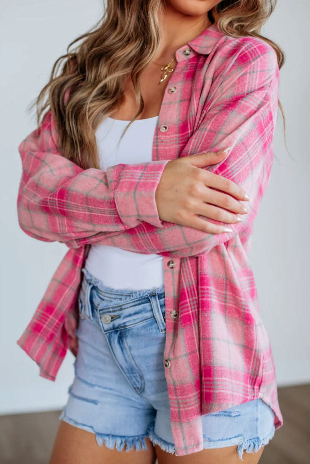 Pink plaid print long sleeve shirt with rounded hem and pockets, styled with casual denim shorts