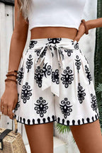White high waist shorts with black tribal geometric print and belted knot detail.