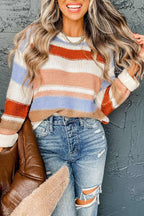 Woman wearing pink striped colorblock round neck drop shoulder sweater with ripped jeans and holding brown jacket