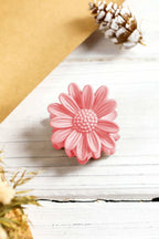 Pink boho daisy flower frosted hair claw clip on white wooden surface