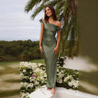 Woman wearing green off-the-shoulder lace-up dress standing outdoors by flowers