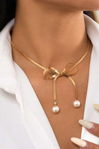Gold pearly bow plated collarbone necklace on woman wearing white shirt