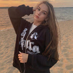 Blackcore Zip Hoodie premium streetwear with printed design and zipper, worn by woman on beach at sunset