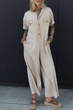 Beige jumpsuit with half placket, chest pockets, short sleeves, and wide leg design for casual wear.