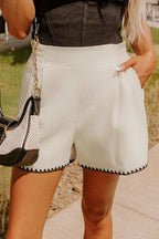 White waffle texture casual shorts with contrasting ricrac hemline worn with black top and handbag outdoors