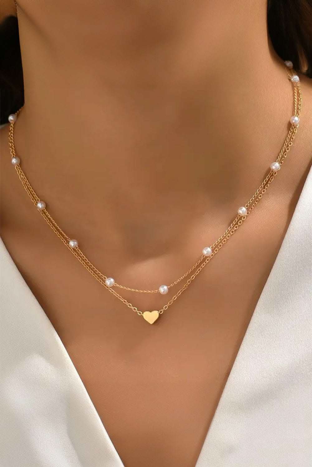 Gold plated heart and pearl detail layered necklace on neck