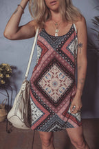 Woman wearing red geometric paisley print sleeveless shift mini dress with a white handbag